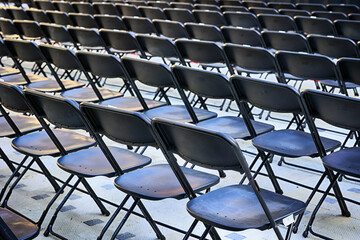 Rzędy czarnych krzeseł stoi na widowni dla publiczności. - obrazy, fototapety, plakaty