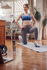 Pretty woman working out at home. Adult lady with beautiful shaped body exercising in the apartment.