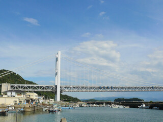 Fototapeta na wymiar 瀬戸大橋とその下の漁村全景。 瀬戸内海の風景。