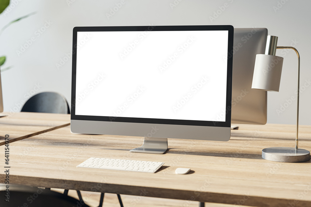 Poster close up of empty white computer screen on wooden office desktop with lamp and supplies on concrete 