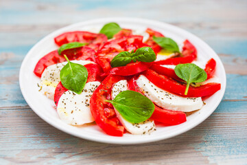 Caprese salad with ripe tomatoes and mozzarella cheese with fresh basil leaves. Italian food.
