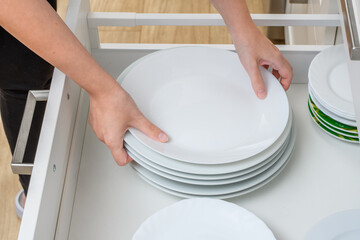 Duże białe talerze wyjmowane z szafki kuchennej - obrazy, fototapety, plakaty