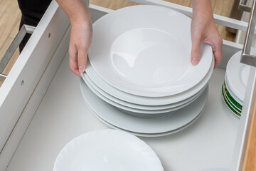 Stos białych talerzy obiadowych trzymany w dłoniach  - obrazy, fototapety, plakaty