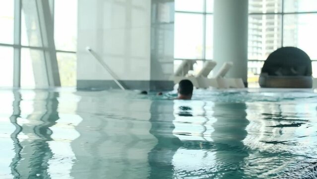 A young athletic man with a young son swims in the pool of an expensive luxury hotel.