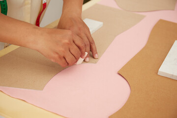 Tailor working with cloth at table in atelier, top view
