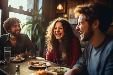 Fotobehang In the warmth of a quaint café, friends share hearty laughter over a meal, creating memories steeped in joy and camaraderie © Davivd
