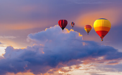 Obraz premium Colorful hot air Balloon flying above the clouds at sunset time before dark coming with colorful light and a beautiful twilight and sunset sky background. hot air balloons sunset