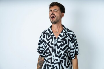 young caucasian man wearing printed shirt angry and mad screaming frustrated and furious, shouting with anger. Rage and aggressive concept.
