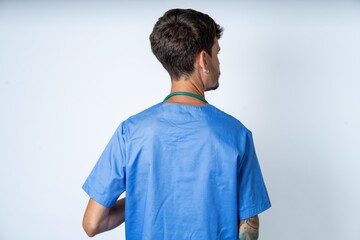 The back side view of a young caucasian doctor man wearing blue medical uniform . Studio Shoot.