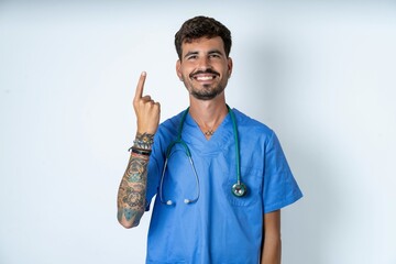 young caucasian doctor man wearing blue medical uniform smiling and looking friendly, showing number one or first with hand forward, counting down