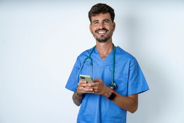 young caucasian doctor man wearing blue medical uniform Mock up copy space. Using mobile phone, typing sms message