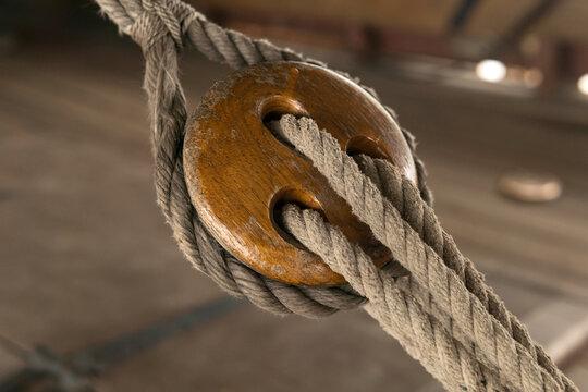 detail of the rigging of an old sailing ship, a wooden triple deadeye block with lanyard