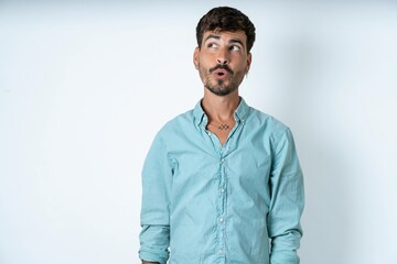 Fototapeta premium Shocked young caucasian man wearing green shirt look empty space with open mouth screaming: Oh My God! I can't believe this.