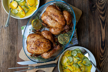 Baked whole chicken with a healthy side salad on rustic wooden table. Top view