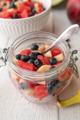 Homemade fruit salad with melon, blueberries, apples and banana in a glass jar