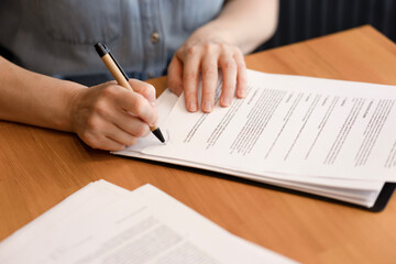 Women's hands sign business documents, contracts, papers in close-up. A woman businessman works in...