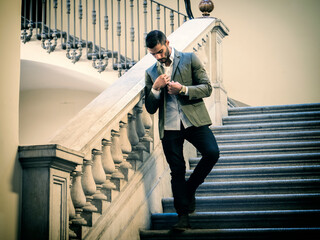 Photo of a man descending a grand staircase in a stylish suit