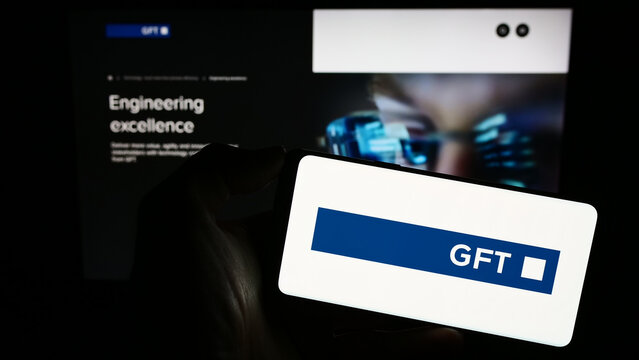 Stuttgart, Germany - 08-21-2023: Person holding cellphone with logo of German IT company GFT Technologies SE on screen in front of business webpage. Focus on phone display.