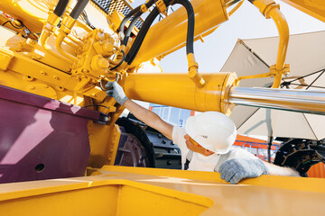 Machinery tractor mechanic checks hydraulic hose system equipment on excavator