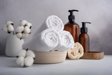 Stack of rolled white towels and dispenser bottles for spa and bathroom