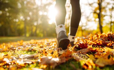 Close-up of feet in hiking boots in a clearing among fallen leaves in a sunny autumn park. Lifestyle concept, outdoor walk.
