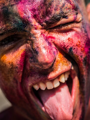 A close up of a painted man with his mouth open, doing silly face with tongue out