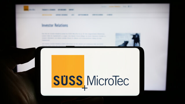 Stuttgart, Germany - 08-22-2023: Person holding cellphone with logo of German technology company S&uuml;ss Microtec SE on screen in front of business webpage. Focus on phone display.