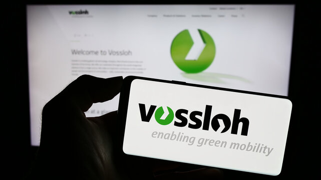 Stuttgart, Germany - 08-24-2023: Person holding cellphone with logo of German rail technology company Vossloh AG on screen in front of business webpage. Focus on phone display.