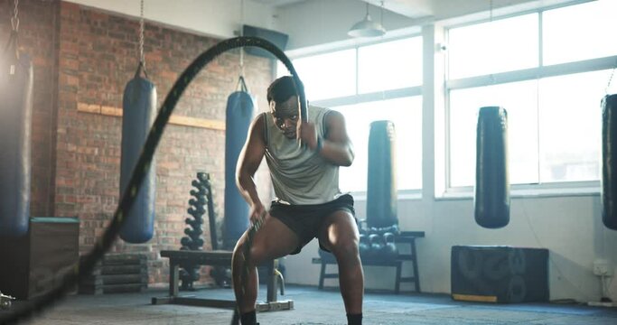 Gym, battle rope and black man with training, wellness and fitness with endurance, muscle and cardio. African person, athlete or power with workout, exercise and bodybuilder with energy and challenge