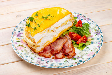 Omelette layered with fried bacon and fresh vegetables. Breakfast.