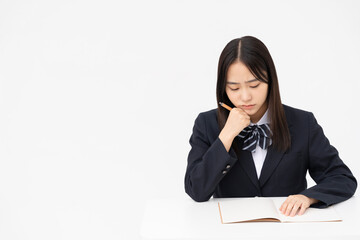 勉強中の制服を着た黒髪ストレートヘアの女子高校生/スタジオ撮影白背景