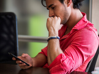 Photo of a man engrossed in his cell phone at a table