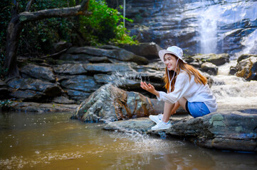 Fototapeta na wymiar asian woman traveller relaxing in deep tropical jungle waterfall 