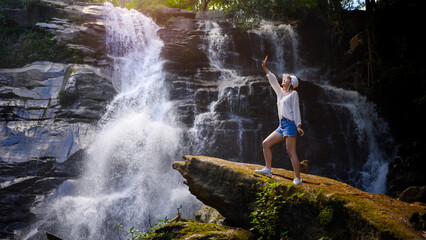 asian woman traveller relaxing in deep tropical jungle waterfall 