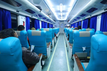Executive class train interior with blue seats, armrests, luggage racks, monitor screens, air...