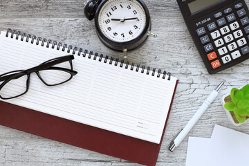 open notebook with glasses. open diary, desk clock, calculator. top view with copy space