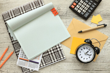 Notepad and desk clock mockup on wooden table, with copy space for text. Flat lay, photo mockup from above.