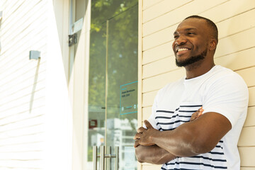 A young African-American man poses for the camera against a wall background