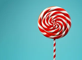Fotobehang Christmas lollipop isolated over light blue background, copy space. New year candy icon with spiral red and white stripes and swirls. Round peppermint hard sugar candy, Xmas and New Year sweet gift © Alina