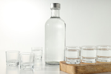 Glass bottle and glasses on wooden stand on white background