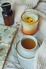 Home decor. Book, knitted blanket, candle, cup of hot tea. Cozy autumn.
