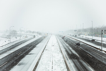 Car driving on asphalt road during snowfall