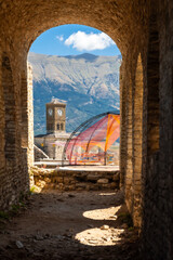 Arches of the fortress of the Ottoman castle of Gjirokaster or Gjirokastra and in the background the church with the clock tower. Albania, Kulla e Sahatit