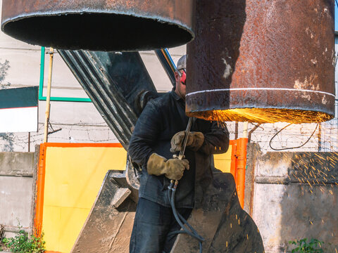 The welder performed welding work. Gas welding works on replacement of large pipes of heating mains. Replacement of an outdated rusty heat supply pipeline. Sparks during gas welding.