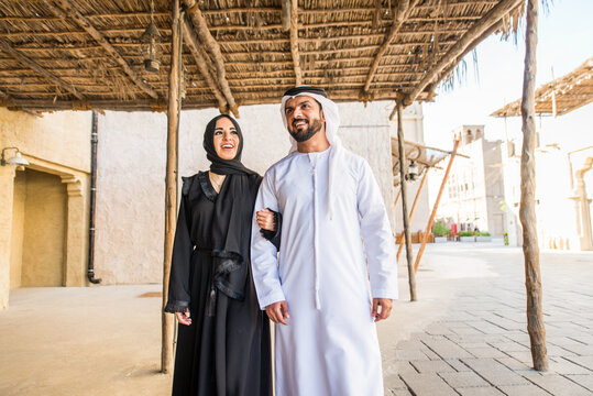 Middle eastern couple of lovers wearing traditional emirati clothing dating outdoors in Dubai - Modern arabian couple meeting and having fun in the city