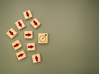 Wooden cubes with red arrows pointing to the dartboard icon are on a green background