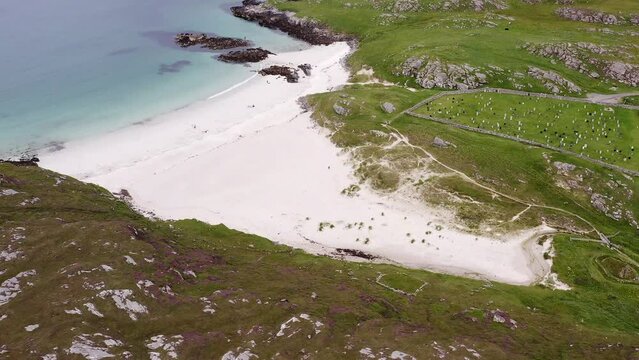 Drone shot of the cemetery and Iron Age House at Bosta beach on the Isle of Great Bernera, near the Isle of Lewis on the Outer Hebrides of Scotland. Ocean, hills, moorland and peatland are visible.