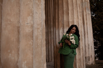 Beautiful woman holding the bouquete of white flowers. The plus size woman dresssed urban style...