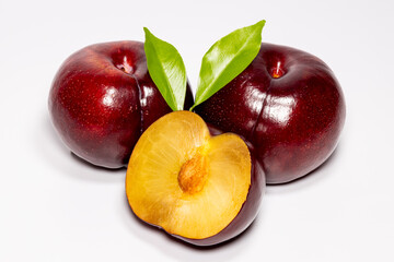 Red Sweet plums with two green leaves isolated on the white background