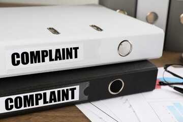 Folders with Complaint labels on office desk, closeup